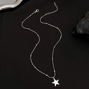 Detail of silver snake chain necklace featuring star pendant and round bead accents