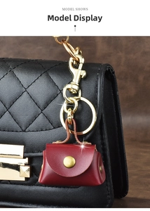 Detail shot of a wine red mini leather bag charm attached to a black quilted handbag