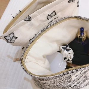 Detailed macro view of minimalist canvas cosmetic bags with embroidery and tweed textures