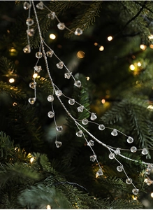 Detail of crystal acrylic garland with pearl beads on a festive Christmas tree branch