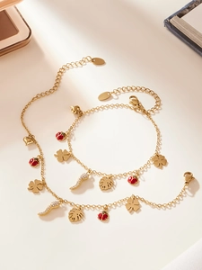 Détail de bijoux dorés avec trèfle, coccinelle et pendentifs piment sertis de strass