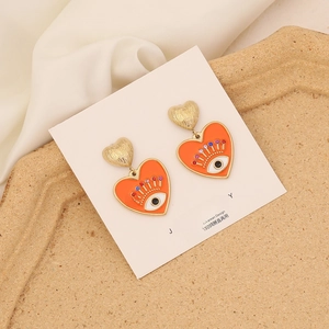 Detail of orange heart enamel earrings with evil eye pattern and colorful crystals