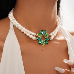 Close-up of double-layer pearl necklace with green gemstone flower pendant on a model
