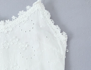 Détails de broderies florales blanches et dentelle ondulée sur l'encolure de la robe