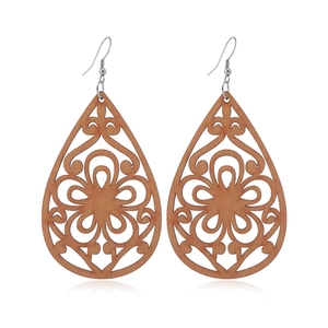 Detailed close-up of teardrop wooden earrings with laser-cut hollow floral patterns
