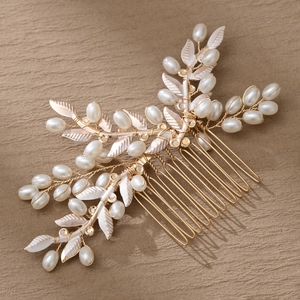 Elegante peine de novia dorado con perlas blancas y hojas sobre tela suave