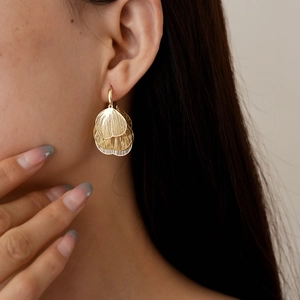 Close-up of a model wearing the golden hollow petal earrings with a metallic finish