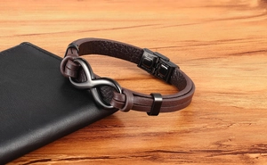 Detail of a brown braided leather bracelet with a dark stainless steel infinity charm