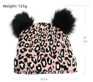 Pink leopard knit beanie detail showing 27cm height and 25cm width with dual pom-poms