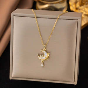 Macro view of gold moon pendant necklace with white inlay and zircon on a jewelry box