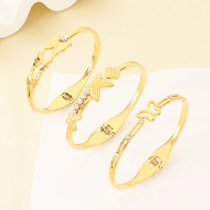 Vista dettagliata di tre diversi bracciali rigidi a farfalla placcati oro con accenti di strass
