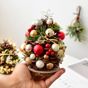 Handcrafted mini Christmas tree made of natural pine cones with colorful ornaments and wood base