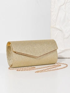 Detail of golden glitter evening clutch bag with metallic chain on white surface
