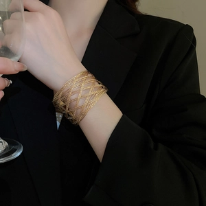 Detailed view of wide gold mesh bracelet with intricate woven texture and open cuff design