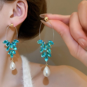 Détail de boucles d'oreilles feuilles bleu menthe avec perle goutte et dorure