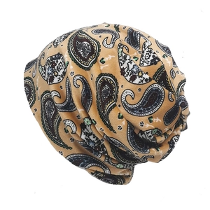 Detail of soft paisley plush beanie featuring ethnic motifs on mustard yellow fabric