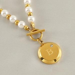 Detail of 18K gold letter B pendant with crystals and white pearl bead necklace
