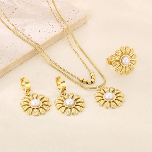 Three-piece gold jewelry set with daisy pearl necklace, earrings, and ring on marble