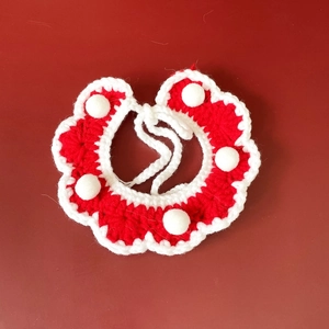 Detail of handmade red and white crochet pet collar with soft pom poms and knit texture