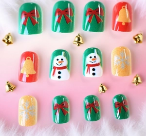 Macro view of Christmas snowman press-on nails featuring red bows and gold bells