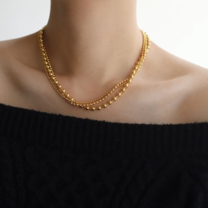 Detail of layered gold-plated bead necklaces showing tiered sizes and polished finish