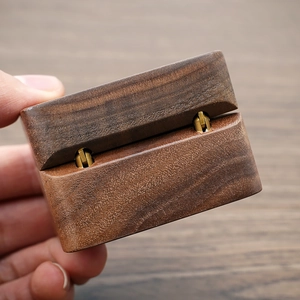Detail view of walnut wood jewelry box with elegant golden metal hinges and smooth finish