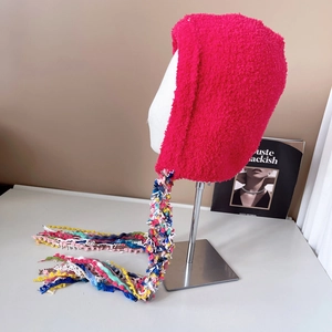 Detail of rose red plush knit hat featuring vibrant colorful tassels and soft texture