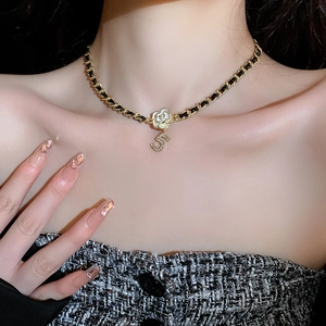 Detailed view of gold-tone chain woven with leather, pearl flower, and crystal number 5