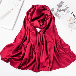 Macro detail of red satin silk scarf draped elegantly next to a perfume bottle