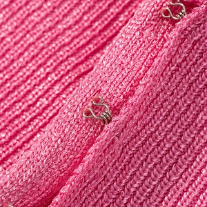 Detail of pink knitted fabric texture and metallic hook-and-eye closure on dress