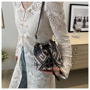 Detail of colorful geometric woven bucket bag with black drawstring and shoulder strap