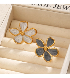 Détail de boucles d'oreilles fleurs vintage en émail blanc et bleu-gris avec bordure dorée