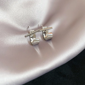 Close-up of minimalist silver geometric U-shaped earrings on soft pink satin fabric