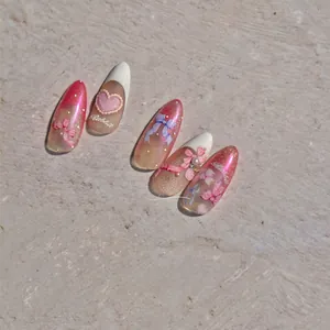 Detailed view of pink iridescent press-on nails with 3D bows, pearls, and heart charms