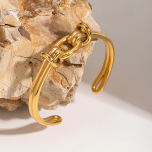 Makroaufnahme einer goldenen Knoten-Manschette auf Naturstein, poliert