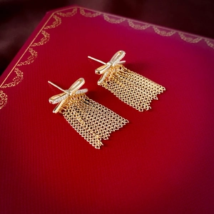 Macro view of gold bow earrings with cubic zirconia and delicate chain tassels