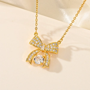 Macro detail of gold bow necklace with white cubic zirconia pavé and center round gem