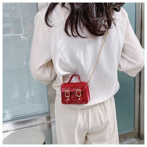 Glossy red mini Cambridge satchel with gold buckles and chain strap on a model