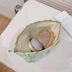 Détail intérieur d'une trousse à maquillage jacquard avec broderie verte et grand espace