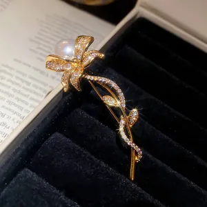 Elegant gold flower brooch with white zircons and pearl in a black jewelry box