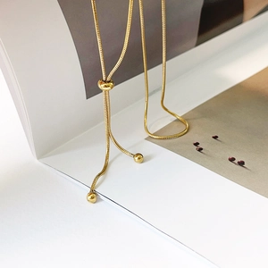 Artistic detail of gold snake chain Y-lariat necklace draped over an open book
