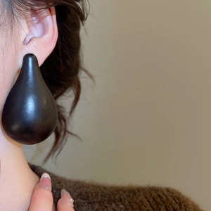 Close-up of elegant black teardrop earring in matte wood finish on model left ear