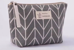 Detail of grey canvas cosmetic bag featuring herringbone pattern and sturdy side handle