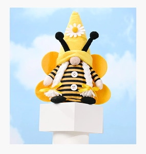 Close-up of a bee gnome plush with white yarn braids, daisy hat detail, and wings