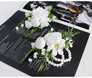 Detailed view of white silk rose boutonniere and pearl wrist corsage set for weddings