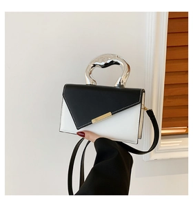 Detail of color-block handbag featuring a unique silver art handle and gold metal lock