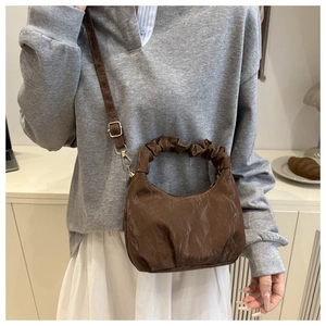 Braune Schultertasche aus PU-Leder mit Falten und goldenen Beschlägen am Modell
