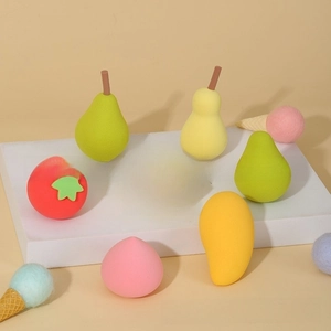 Detail showing various fruit-shaped makeup sponges on a minimalist display stand