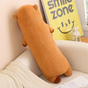 Detail view of cartoon capybara long plush pillow case on a sofa with warm cozy lighting