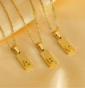 Detail of square gold pendants with frosted finish and 3D letters A, B, and C